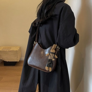 Detail view of a vintage brown bucket bag with a cute rabbit pendant on a model