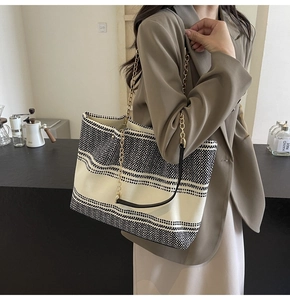Detailed view of striped woven tote bag featuring gold chain and leather shoulder straps