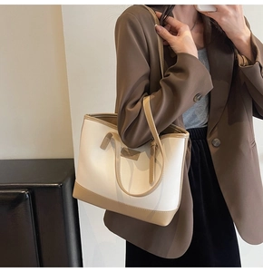 Detail of the minimalist tote bag featuring a bicolor cream and khaki leather finish