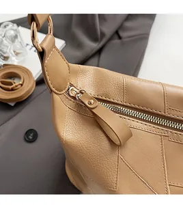 Detailed close-up of smooth gold-tone zipper and lychee texture on tan PU leather handbag