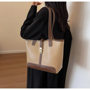 Detail view of khaki and brown tote bag with metal buckle on a model's shoulder