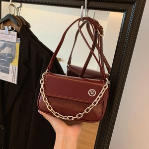 Close-up of a burgundy glossy shoulder bag featuring a silver logo and chain decoration