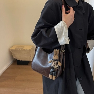 Detail of vintage brown bucket bag featuring a plush rabbit pendant on leather strap