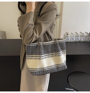 Detail of a large woven tote bag with black and white stripes and gold chain strap