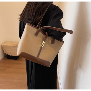 Close-up of contrast leather tote bag with gold-tone twist lock and shoulder strap
