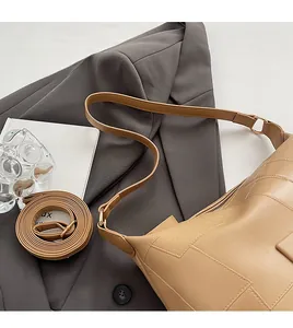 Detail of adjustable leather strap and hardware on a beige shoulder bucket bag