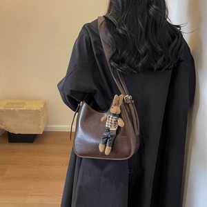 Detail of dark brown glossy leather bucket bag with a cute plaid rabbit charm