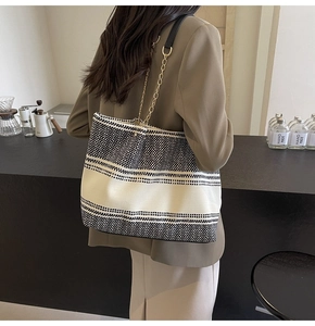 Detail of black and white woven texture tote with gold chain strap on café counter
