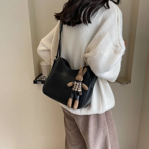 Detail of black leather hobo bag with a cute brown rabbit charm on model