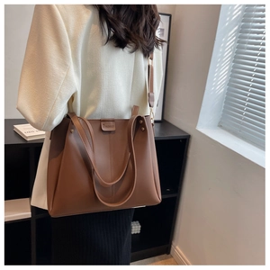 Close-up of caramel brown tote bag showing matte faux leather texture and top handle detail