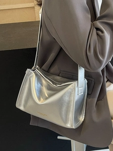 Sac bandoulière argenté métallisé avec bandoulière réglable porté sur un blazer