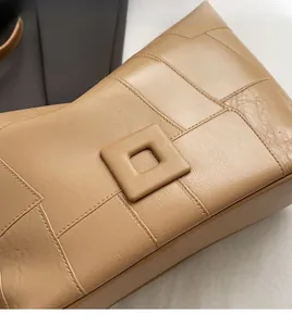 Close-up of the stylish leather stitching and beige square buckle on the handbag
