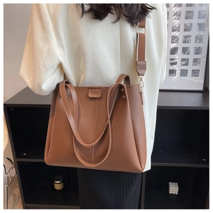 Detail of classic brown tote bag with embossed logo and wide woven shoulder strap