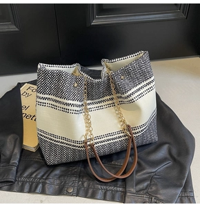 Detail of large woven tote bag with geometric patterns, chain handle and leather strap
