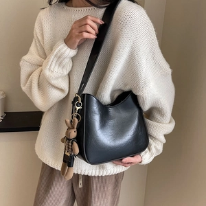 Detail of black PU leather bucket bag featuring a cute knitted rabbit pendant charm