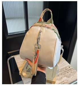 Détail du sac à dos crème avec broderies florales raffinées et boucles en métal argenté