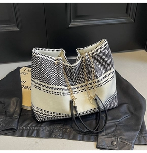 Close-up of black and white woven texture tote bag with golden chain and leather straps