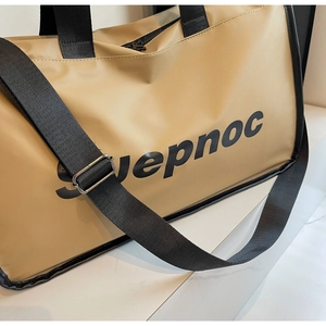 Detail of khaki travel bag showing SUEPNOC logo, black handles and wide nylon shoulder strap