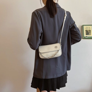 White leather crossbody bag with silver chain strap shown on model in grey suit