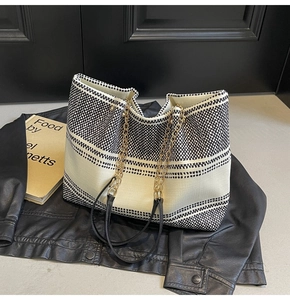 Close-up of contrast woven tote bag showing geometric patterns and metal chain strap