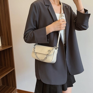 Detail shot of the cream white crossbody bag with decorative silver chain on a model