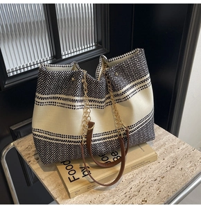 Detail of polka dot and stripe tote bag with gold chain strap and brown leather accent