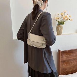 Chic cream-colored crossbody bag shown with silver chain and leather strap on a model