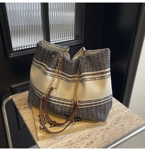 Detailed shot of large canvas tote bag featuring geometric patterns and chain straps