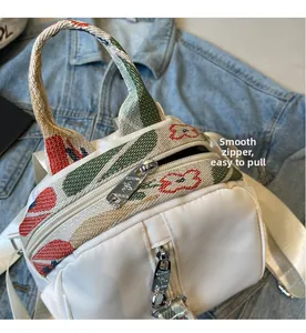 Détail de la fermeture éclair argentée sur sac à dos blanc avec sangle colorée
