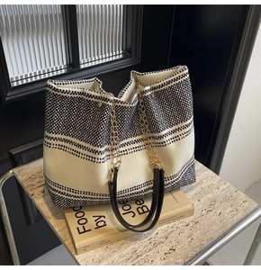 Detail of canvas tote bag showing black and white stripes and metal chain handle