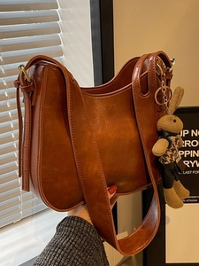 Brown leather bucket bag with a cute rabbit charm shown in a stylish side view