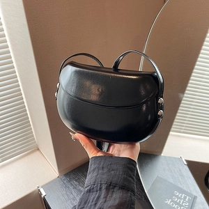 Vue détaillée d'un sac selle en cuir noir brillant avec des détails en métal argenté