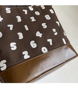 Détails du sac fourre-tout en toile avec imprimés numériques et empiècement en cuir marron