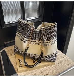 Close-up of contrast weave tote bag with gold chain strap resting on books