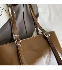 Détail du sac à bandoulière en cuir ciré marron brillant avec boucle en métal argenté