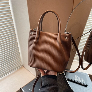 Dettaglio della texture a pieghe marrone sulla borsa a secchiello in pelle PU con fibbie