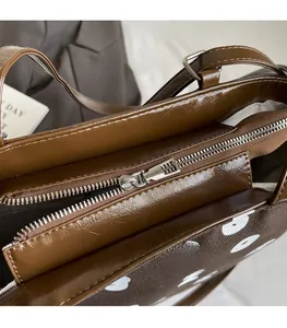 Détail de la fermeture éclair en métal argenté fluide sur un sac cabas marron chic