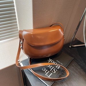 Détails du sac besace en cuir caramel avec rivets argentés et bandoulière réglable