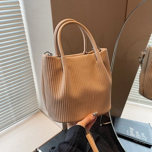 Dettaglio della trama della borsa a secchiello in velluto beige e anelli metallici