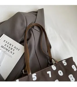Détail du sac cabas en toile marron foncé avec imprimé numérique et anses en cuir