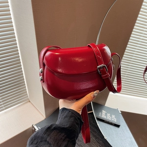 Détail d'un sac besace rouge avec rivets argentés et bandoulière réglable en cuir