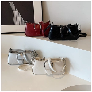 Detail view of stylish underarm bags in red, black, silver, and cream with metal buckles