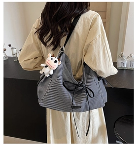 Borsa tote in tela a righe bianche e nere con fiocco e ciondolo a mucca sulla spalla