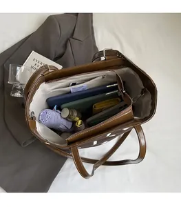 Vue intérieure montrant la grande capacité du sac cabas en cuir marron avec des objets divers