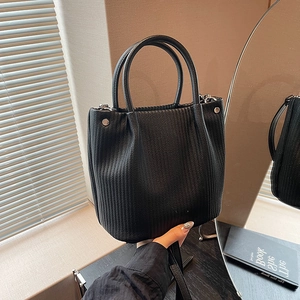Dettaglio della borsa a secchiello nera con texture plissettata e borchie in metallo argento