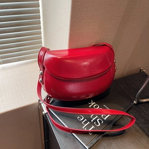 Vue détaillée d'un sac besace rouge avec rivets argentés sur un livre noir