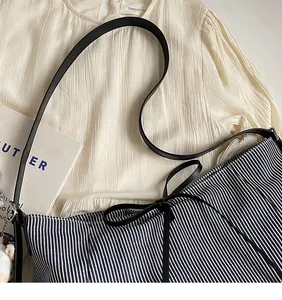 Dettaglio della borsa tote a righe bianche e nere con manici in pelle e fiocco