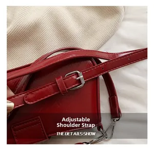 Detail of red PU leather handbag featuring adjustable shoulder strap and silver hardware