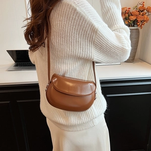 Sacoche marron en cuir avec clous porté par un mannequin en pull en maille