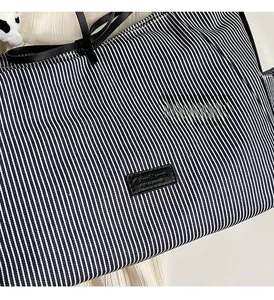 Dettaglio della borsa tote in tela a righe blu e bianche con trama in pelle nera